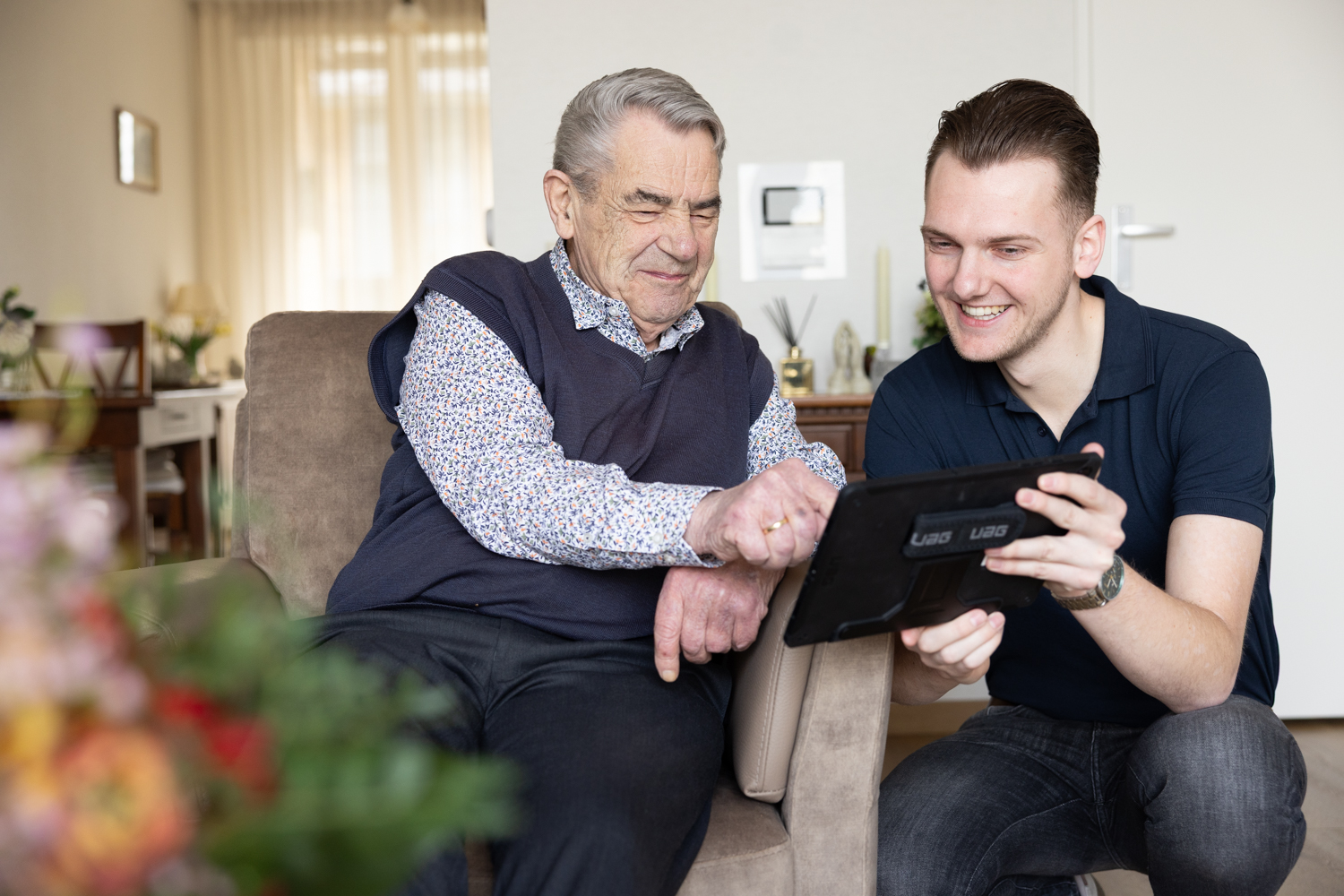 Cliënt in thuiszorg krijgt uitleg over tablet